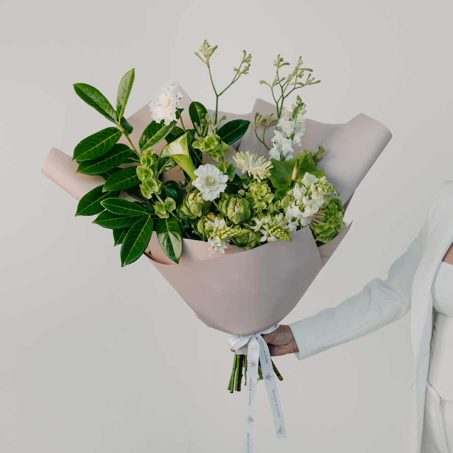 Bouquet of flowers held by a person against a light gray background