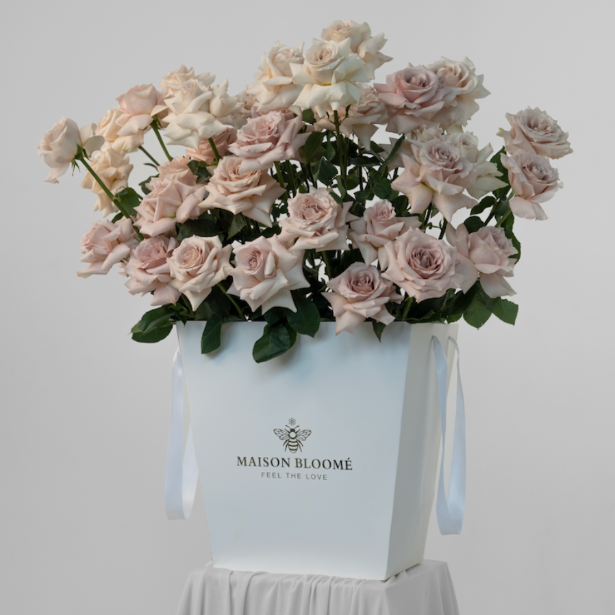 Bouquet of pink roses in a white box with 'Maison Bloome' branding on a white background