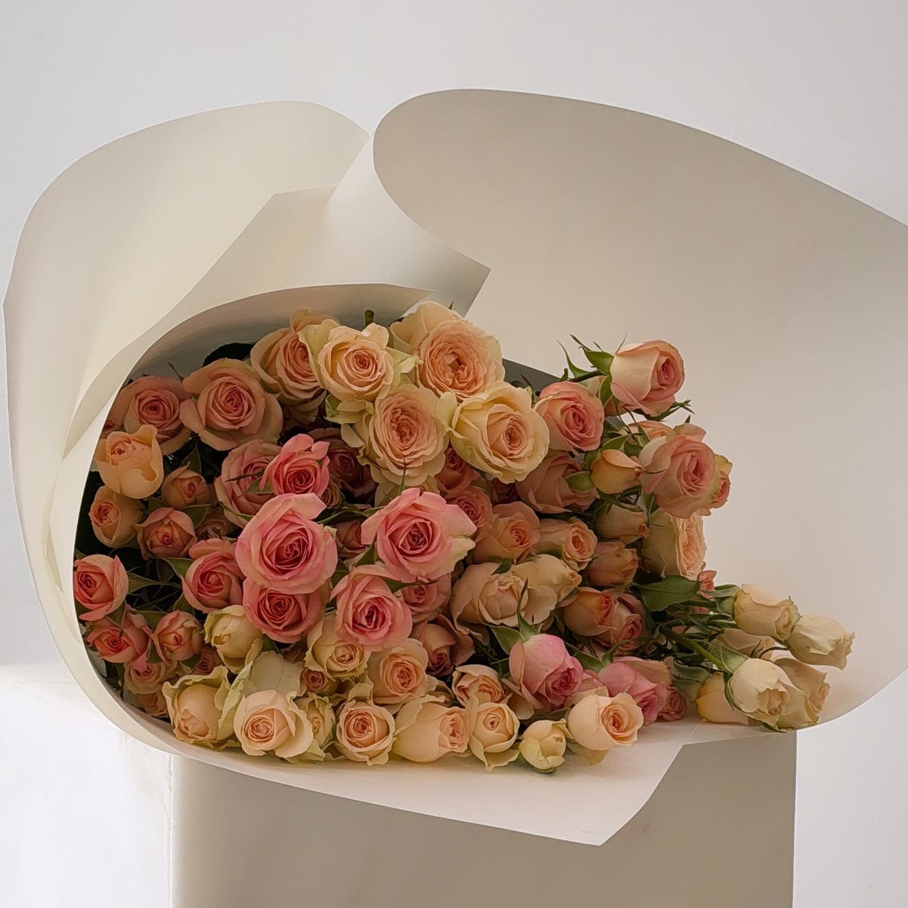     Blush spray rose bouquet with 20 stems displayed on a pedestal.