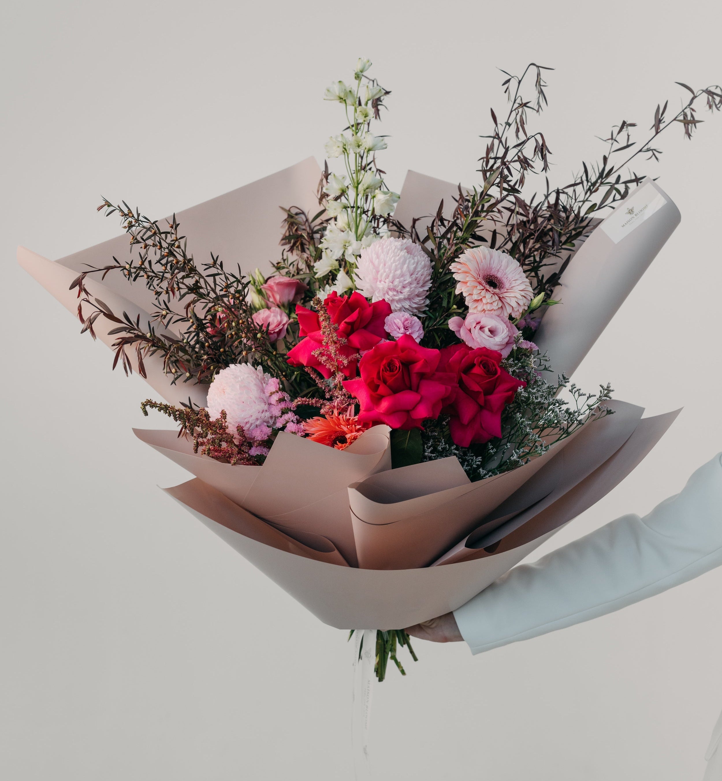 Red and pink mixed flower bouquet wrapped in paper by Maison Bloomé florist Adelaide with same day delivery